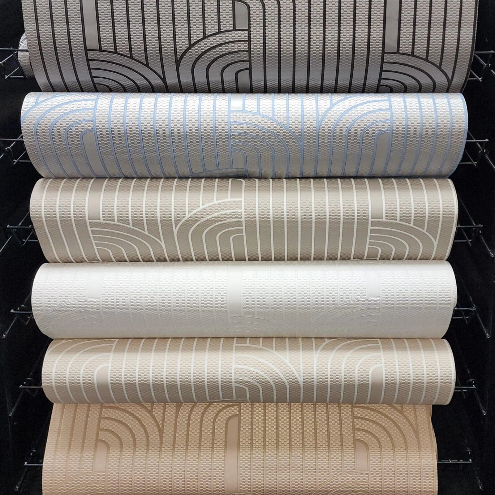 Stack of wallpaper rolls with different patterns and colors on a black background