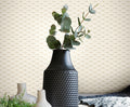Black textured vase with green leaves against a textured beige wall