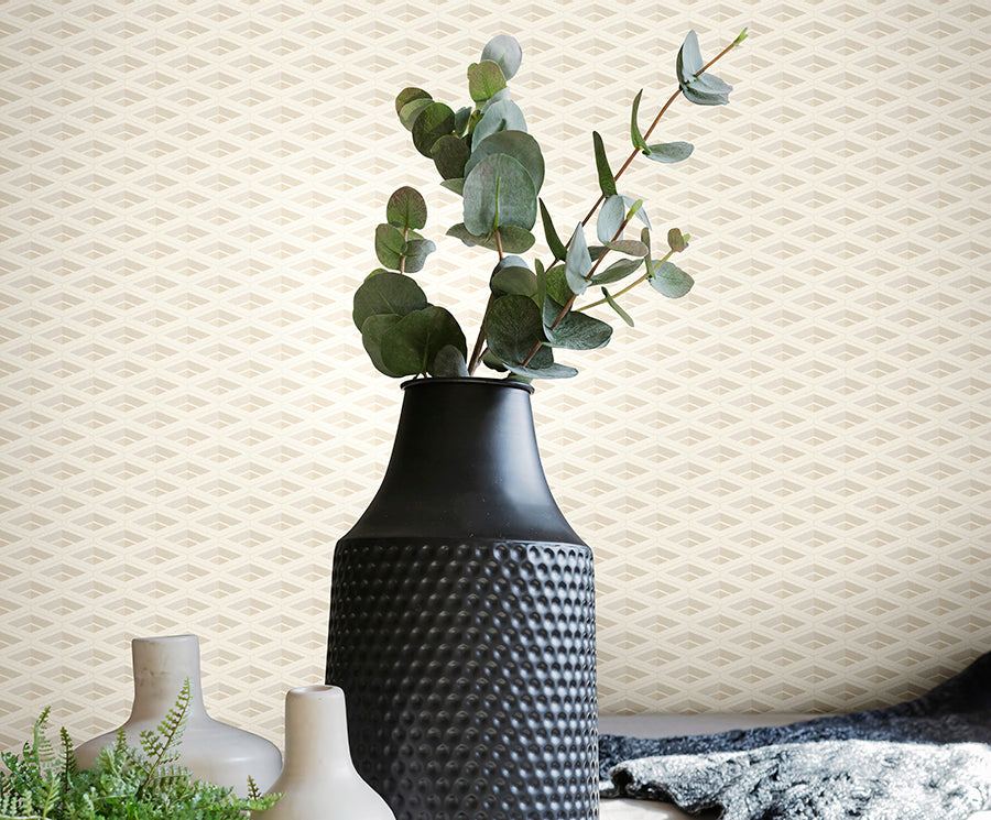 Black textured vase with green leaves against a textured beige wall